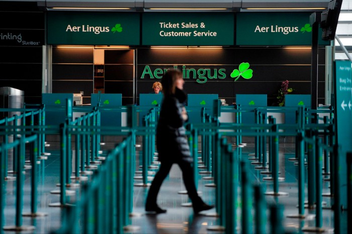 Пешеход проходит мимо стойки билетной кассы и обслуживания клиентов Aer Lingus Group в зале вылета аэропорта Дублина.