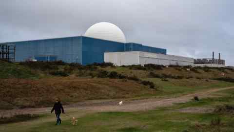 Мужчина проходит свою собаку мимо атомной электростанции Sizewell B