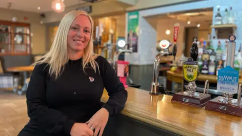 BBC Landlady Beccy Webster, сидя перед баром паба