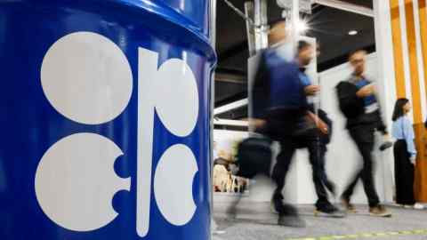 Люди проходят мимо установки с изображением ствола масла с логотипом OPEC