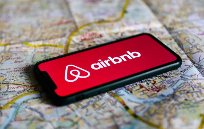 Логотип Airbnb отображается на экране телефона, заложенного на карте Кракова