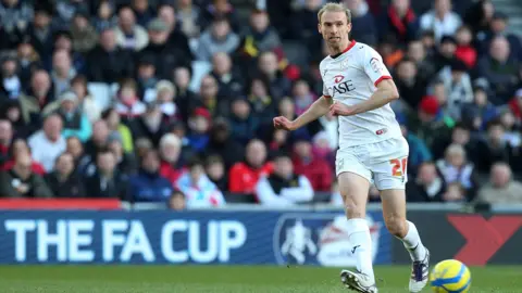Getty Images Chadwick, в полном белом комплекте MK Dons, проходя мяч.