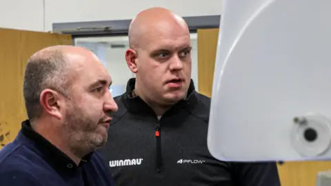 Winmau Lee Huxtable смотрит на экран компьютера с бывшим чемпионом мира Майклом Ван Гервеном, чтобы спроектировать свои дротики