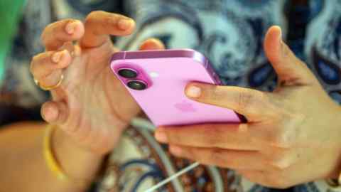 Клиент держит и осматривает розовый Apple iPhone 16 в Apple Store