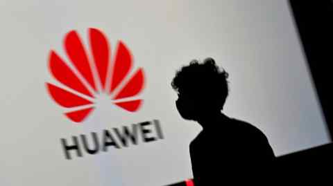 Человек проходит мимо большого экрана, показывая логотип Huawei