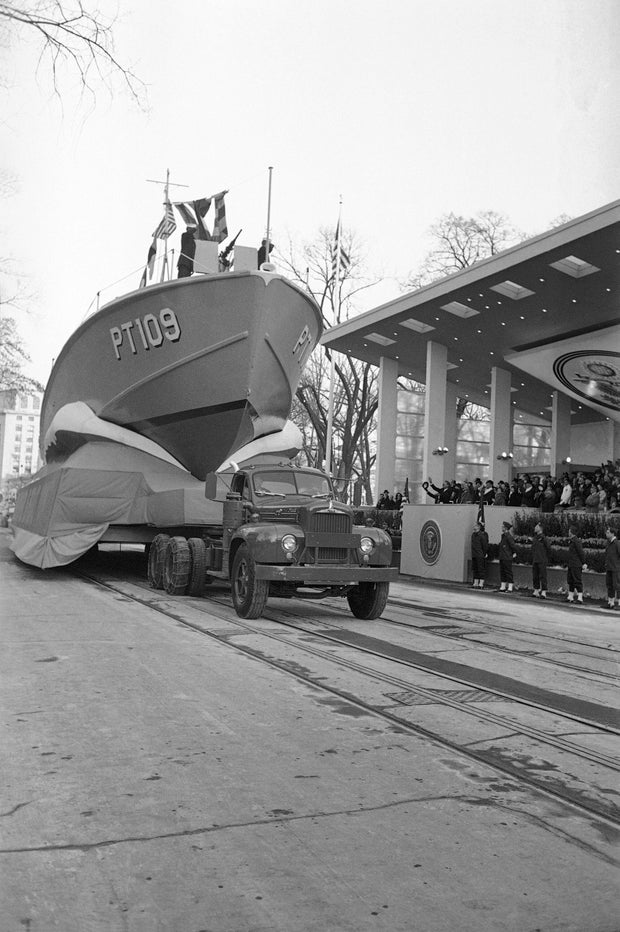 20 января 1961 года на военно -морской лодке выходит высоко над Пенсильванским проспектом, когда первый парад проходит на президентском рецензированном стенде. Президент Джон Кеннеди волнает морякам на борту. 