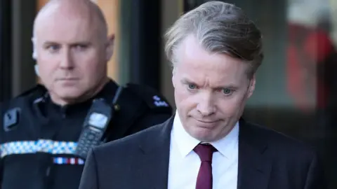 PA Media Craig Whyte, мужчина среднего возраста с песчаными волосами, за пределами корта. Он смотрит вниз, носит черный пиджак, белую рубашку и фиолетовый галстук.